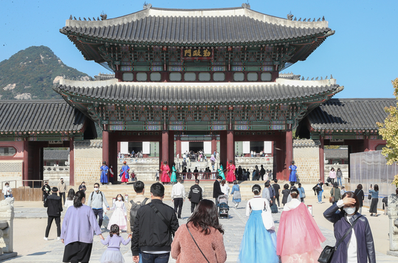 Tourists stroll through the courtyard of Gyeongbok Palace in central Seoul on a sunny fall day on Sunday as the leaves begin to change color. [YONHAP]