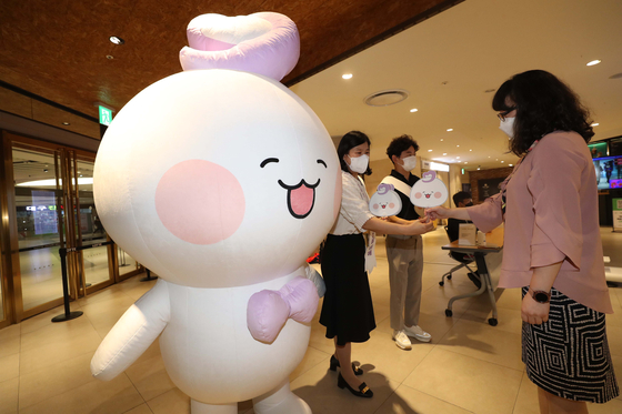 Joice, a character representing Lotte Shopping's counseling center Rejoice, stands next to an employee giving a fan to a passerby. [YONHAP]