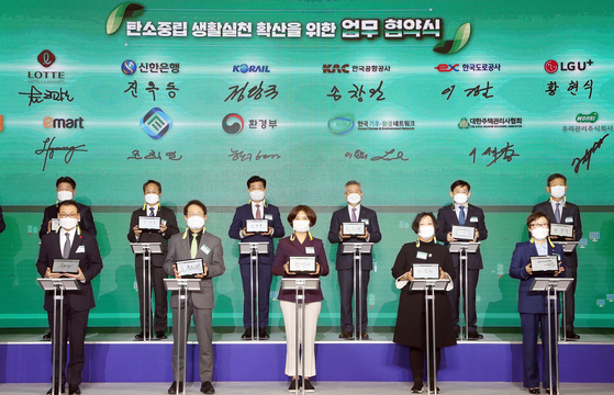 Shinhan Bank CEO Jin Ok-dong, second from left in the second row, and Environment Minister Han Jeoung-ae, center in the front row, pose for a photo after signing an agreement to join forces to strengthen efforts to achieve carbon neutrality Monday at Coex in Gangnam District, southern Seoul. [SHINHAN BANK]  