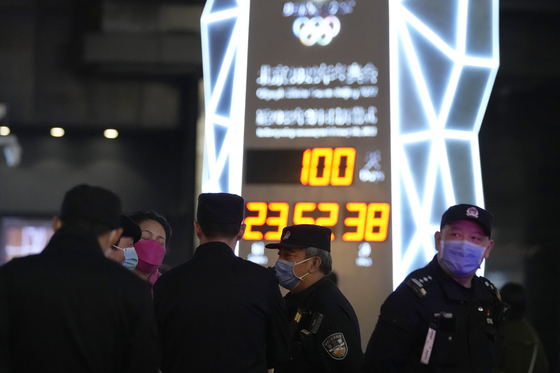 Police officers keep watch near a countdown clock as it crosses into the 100 days countdown to the opening of the Winter Olympics in Beijing, China, Tuesday, Oct. 26, 2021. [AP/YONHAP]