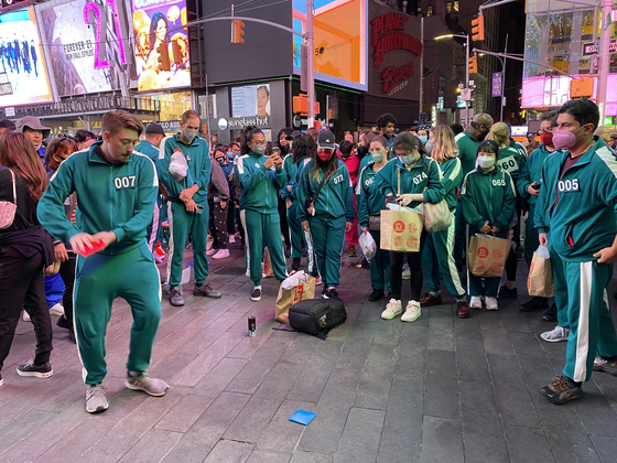 Participants of the "2021 Korea Tour with Squid Games in NY" play ddakji, a Korean game using folded paper tiles, in Times Square, New York, on Tuesday. The program is hosted by the Korea Tourism Organization, inviting 80 people to try out the games featured on "Squid Game" and visit Korean attractions such as Koreatown. [YONHAP] 