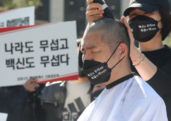 A man whose relative died after getting a Covid-19 vaccine has his head shaved at a press conference as he filed a petition with the Constitutional Court in Seoul on Thursday. An association of family members of Covid-19 vaccination victims demanded compensation from the government in the petition. [NEWS1]