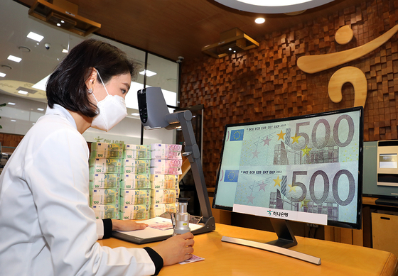 A Hana Bank employee looks at a real 500 euro note, bottom, and a counterfeit on a computer monitor. According to the bank Thursday, it spotted a 500 euro note forged using a special ink that can only be distinguished when seen through high-performance optical devices using ultraviolet and infrared light. The bank said the case has not yet been reported to international institutions like the Interpol. It will submit a research report to relevant institutions for international investigation. [HANA BANK]
