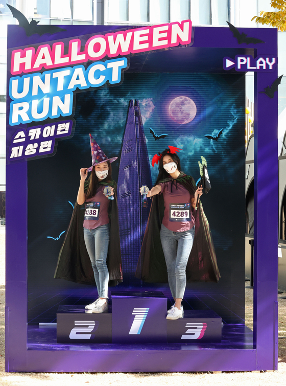 Models in Halloween costumes stand on the podium for the "Lotte World Tower Halloween Untact Run" marathon event at Lotte World Tower in Songpa District, southern Seoul, on Thursday. Rather than gathering at the same place to start, participants can start anywhere and track their pace and distance using a GPS-based running app. The event runs through Oct. 31. [YONHAP] 