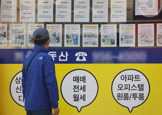A man looks at notices of apartments on sale posted on a window at a realtor's office in Seoul on Sunday. While the government pressures banks to cut loans, trading of relatively cheap apartments in Seoul, priced under 600 million won ($510,000), is becoming popular, according to real estate app Zigbang on Sunday. [YONHAP]