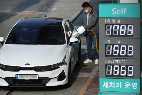 A man fills up his car at a gas station in Seoul on Sunday. Average gasoline prices nationwide rose on week by more than 30 won ($0.03) per liter, or 1.7 percent, to 1,762.8 won per liter in the fourth week of October. The government will cut fuel taxes by 20 percent from Nov. 12 to help ease the burden on households and companies due to hefty oil prices. [YONHAP]