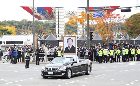 A crowd watches the state funeral procession for former President Roh Tae-woo pass by Olympic Park in Songpa District, southern Seoul, on Saturday. [NEWS1]