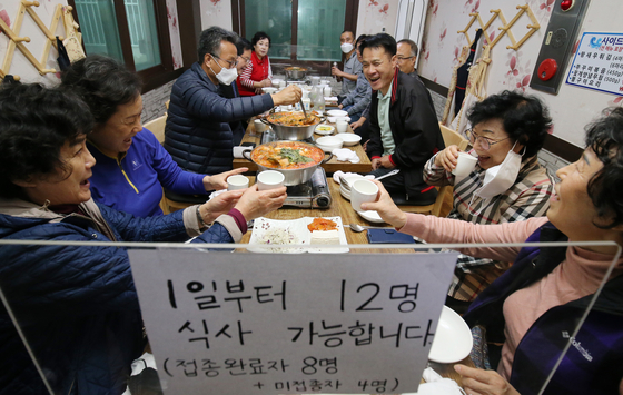 A group of 12 people have meal together at a restaurant in Daejeon on Monday, the first day of the introduction of the phased social distancing "With Corona" scheme which allows up to 12 people to gather socially in non-metropolitan areas. [NEWS1]