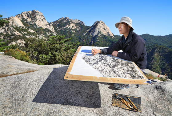 Ink-and-wash painter Kim Suk-hwan sketches mountaintops seen from Wonhyo Peak, 505 meters (1,656 feet) above ground on Mount Bukhan, northern Seoul. [PARK SANG-MOON]