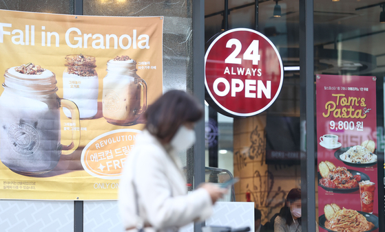 A sign saying "24 Hours Always Open" hangs in front of a cafe in Gangnam District, southern Seoul, on Monday. The government announced a draft for the "With Corona" scheme that will allow restaurants and bars to stay open 24 hours a day. [YONHAP]