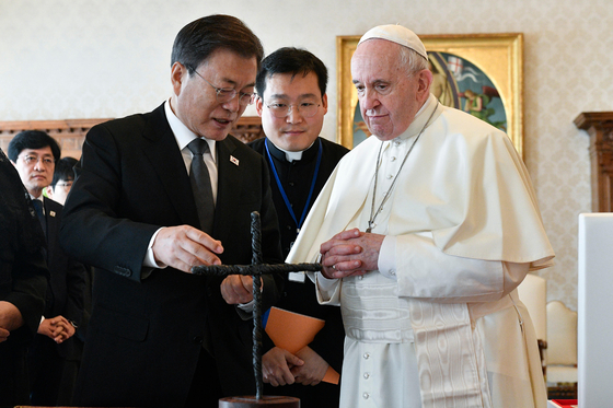 President Moon Jae-in, left, describes his gift to Pope Francis, right, during their meeting at the Vatican on Friday. The gift is a cross made from the barbed wires at the demilitarized zone separating the two Koreas. Moon held a private audience with the pope, their second time since first meeting in 2018. [YONHAP]