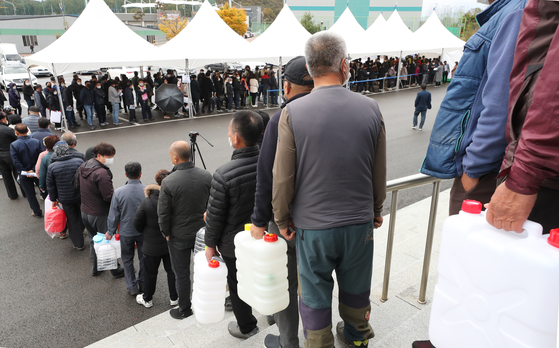 Large crowd lines up in front of a gym in Iksan, North Jeolla, on Tuesday waiting to get urea solutions for their diesel vehicles supplied by Aton Industry, the regional urea solution producer. [YONHAP]