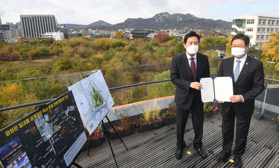 Seoul Mayor Oh Se-hoon, left, and Culture Minister Hwang Hee pose on Wednesday for a photo, holding up a memorandum of understanding for building the so-called Lee Kun-hee Museum, with Seoul's Songhyeon-dong, where the museum will be built, in the background. [NEWS1]