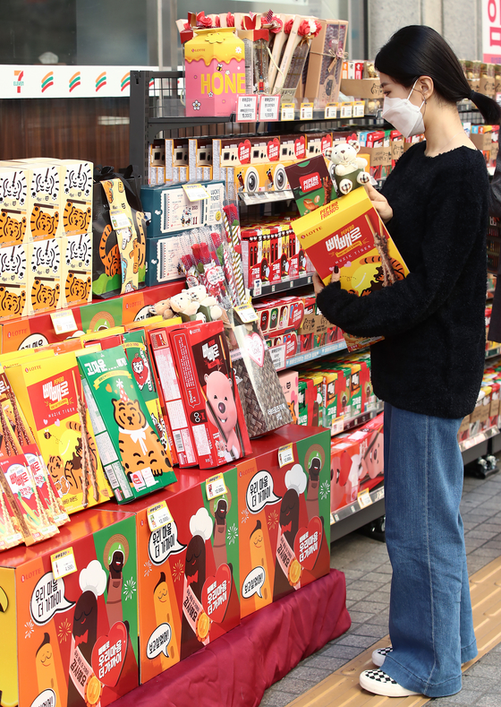 A customer shops for pepero at a 7-Eleven store in Seoul on Thursday, Nov. 11, to celebrate Pepero Day, the holiday named after the chocolate-covered snack that couples gift each other.[YONHAP]
