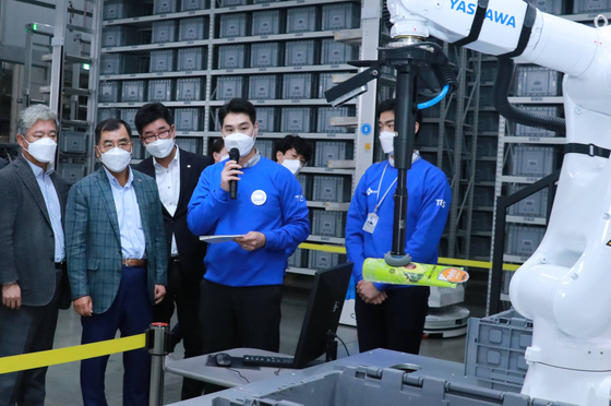 CJ Logistics CEO Kang Sin-ho, second from left, observes a demonstration of a robot hand that can pick up and place packages on a conveyor belt at the company’s innovation center in Dongtan, Gyeonggi. [CJ LOGISTICS]