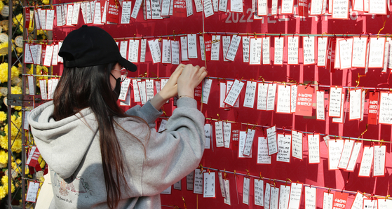 A 2022 College Scholastic Ability Test (CSAT) test taker hangs a slip of paper with a note with her wish for the upcoming exam on Thursday, at Jogye Temple in Jongno District, central Seoul, on Sunday. [NEWS1]