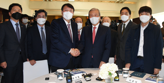 People Power Party presidential candidate Yoon Seok-youl (center left) shakes hands with former party leader Kim Chong-in  (center right) at the launch of Kim's new book in Yongsan District, central Seoul, on Monday. At the far right is the current party chairman, Lee Jun-seok. [YONHAP]