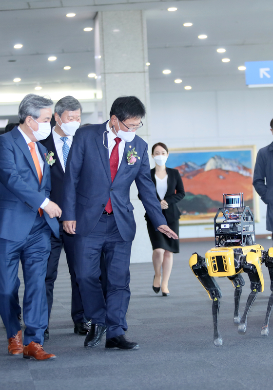 Head of Land Infrastructure and Transport Committee Lee Hun-seung waves at four-legged robot Spot at the "2021 Smart Construction Expo" held at Kintex in Goyang, Gyeonggi, on Wednesday. The robot is used to collect data about construction sites and monitor progress. About 200 companies that use innovative technologies in construction attended the event, which runs through Friday. [YONHAP] 