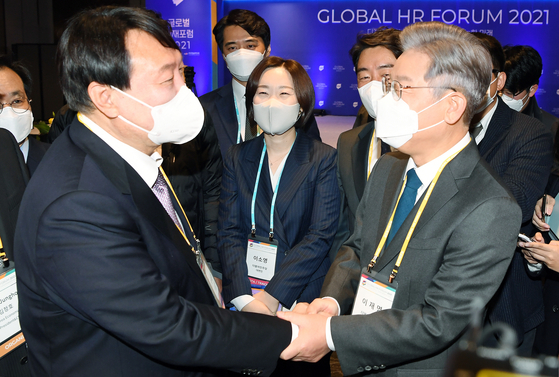 Opposition People Power Party (PPP) presidential candidate Yoon Seok-youl, left, shakes hands with Lee Jae-myung of the ruling Democratic Party (DP) in the Global HR Forum hosted by the Korea Economic Daily on Sept. 10. [JOINT PRESS CORPS]