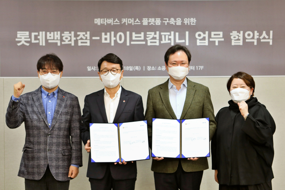 Lotte Department Store CEO Hwang Beom-seok, second from left, and Vaiv Company CEO Lee Jae-yong, second from right, pose for a photo to celebrate the signing of the memorandum of understanding between the two companies at the main Lotte Department Store branch in central Seoul on Thursday. [LOTTE SHOPPING]