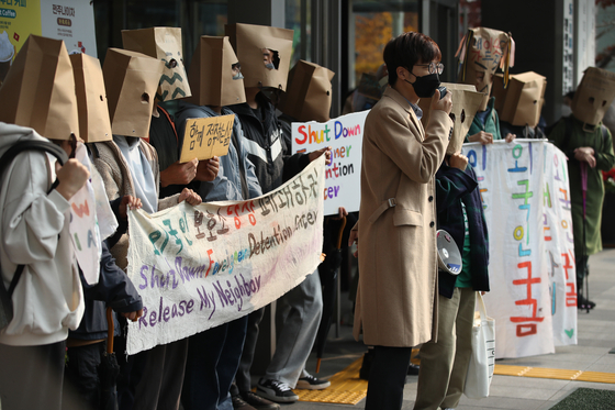 A group of human rights activists, covering their faces with paper bags, stage a rally in front of the National Human Rights Commission in Seoul on Thursday to demand the shutdown of immigration processing centers, accusing them of functioning like detention centers. [YONHAP]