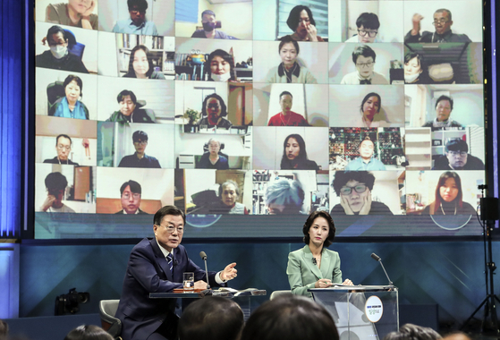 President Moon Jae-in, left, answers questions from the audience at a town hall Sunday evening in a studio in Yeouido, western Seoul, attended by some 300 people both in person and virtually. [JOINT PRESS CORPS]