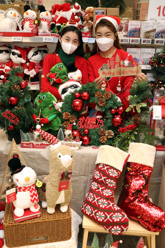 Models hold up Christmas-related items on sale at Emart’s Yongsan branch in central Seoul on Thursday. Emart is offering discounts on Christmas decorations through Dec. 8. [EMART]