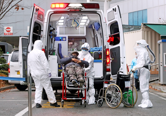 Medical staff in protective gear unload a patient infected with Covid-19 at the Seoul Medical Center in eastern Seoul on Tuesday. [YONHAP]