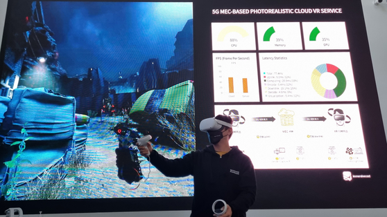 An on-site staff shows visitors how the cloud virtual reality (VR) game Alyx works, wearing a VR headgear, during a press tour of the Metaverse Playground on Monday in Coex, Southern Seoul. [YOON SO-YEON]