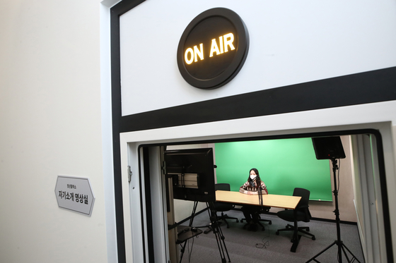 An employee sits in a video recording booth at Seoul Citizens' Hall in Jung District, central Seoul, on Monday. The Citizens' Hall has set up three booths equipped with laptops, wireless microphones, green screens and other equipment that job seekers can use for remote job interviews. [YONHAP] 