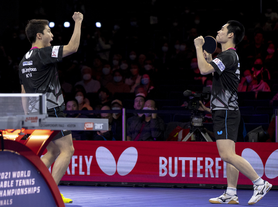 Lim Jong-hoon, left, and Jang Woo-jin celebrate during the men's doubles semifinal match against Japan's Togami Shunsuke and Uda Yukiya at the 2021 World Table Tennis Championships Finals in Houston, Texas, on Sunday. [XINHUA/YONHAP]