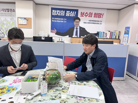 Lee Jun-seok, right, chairman of the main opposition People Power Party (PPP), speaks with officials at PPP Rep. Chang Je-won’s office in Sasang District in Busan on Wednesday, after canceling official activities since Tuesday. [NEWS1]
