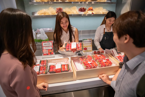 Food content creator Olivia Lee, center, presents Korean strawberries during a promotional event in Singapore last year. [OLIVIA LEE]