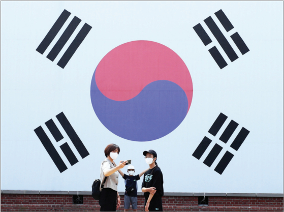 People take a photo in front of a large Korean flag at Seodaemun Prison History Hall in western Seoul, ahead of this year’s Liberation Day on Aug. 15. [YONHAP]