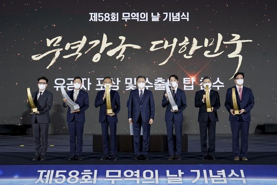 President Moon Jae-in, center, poses with executives of companies recognized with “Export Tower” awards for their contributions to Korea’s exports and trade including Studio Dragon, Samsung Electronics, Krafton and H-line Shipping in a ceremony to mark the 58th Trade Day at Coex Convention and Exhibition Center in Samseong-dong, southern Seoul, Monday. [JOINT PRESS CORPS]