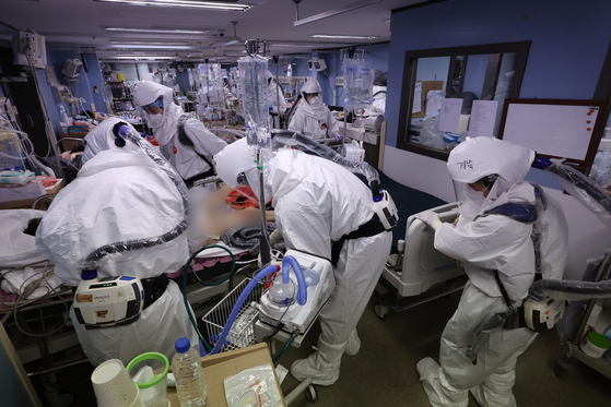 Medical staff treat patients in an intensive care unit at a hospital in Pyeongtaek, Gyeonggi, on Monday. With the recent spike in cases, 80.4 percent, or 994 I.C.U. beds were in use out of 1,237 total throughout the country as of Sunday. [YONHAP]