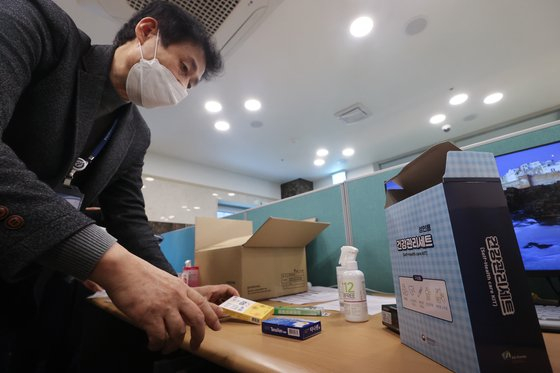A health official displays the contents of the Covid-19 treatment kit that is distributed to patients who get treated for the virus at home, at a residential treatment center in Yeongdeungpo District, western Seoul, on Nov. 18. The kit contains medical items that an average person can readily use such as flu medicine, an oximeter, a thermometer and hand sanitizer. [JOINT PRESS CORPS]