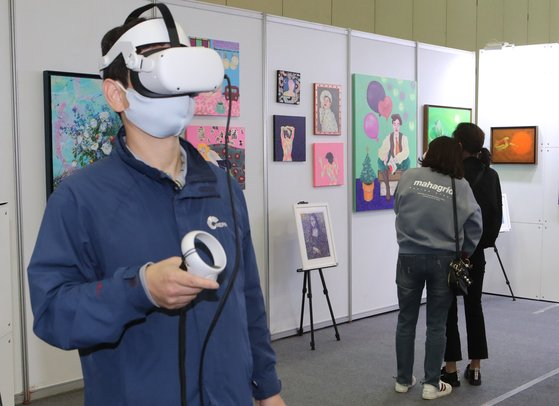 A visitor uses a virtual reality headset during a blockchain technology exhibition “NFT Busan 2021” in Bexco, Busan, on Nov. 4. [SONG BONG-GEUN]