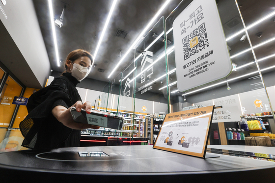 An employee demonstrates how to enter an unmanned Emart24 store in Coex, southern Seoul, by scanning a QR code. [YONHAP]