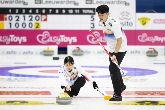 Kim Min-ji, left, and Lee Ki-jeong compete during the mixed doubles round robin match between the United States and Korea at the Beijing 2022 Olympic Qualification curling tournament in Leeuwarden, Netherlands on Wednesday. [EPA/YONHAP]