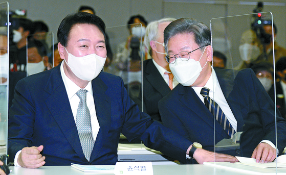  Opposition People Power Party (PPP) presidential candidate Yoon Suk-yeol, left, talks with his rival Lee Jae-myung of the ruling Democratic Party (DP) at an event on December 9 to commemorate the 21st anniversary of the awarding of Nobel Peace Prize to former President Kim Dae-jung.  [JOINT PRESS CORPS]