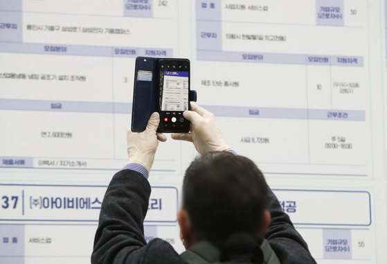 A job seeker taking pictures of job opening during a job fair held in Suwon on Dec. 2. Jobs continued to grow for nine consecutive months. However, the resurgence of Covid-19 has started to show. [YONHAP] 