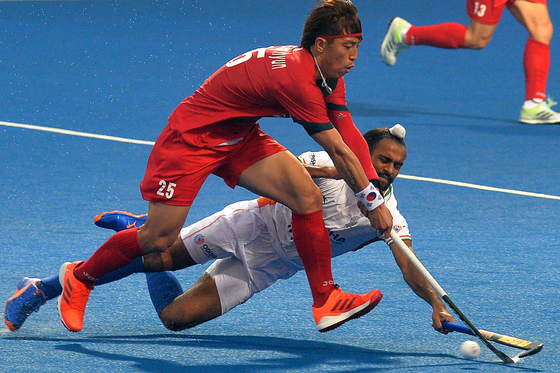 Jang Jong-hyun, left, dodges past India's Jaskaran Singh during a men's field hockey match between Korea and India at the Asian Championship Trophy tournament in Dhaka, Bangladesh on Tuesday. Korea held defending champion and Olympic bronze-medalists India to a 2-2 draw in their opening match. [AFP/YONHAP]