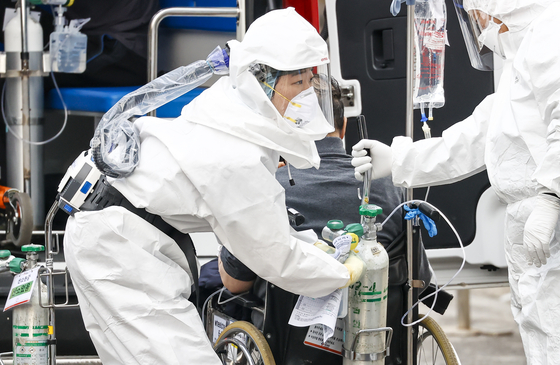 A medical worker in a hazmat suit transfers a Covid-19 patient to the Seoul Medical Center in Jungnang District, eastern Seoul, on Thursday. The center said it has recorded 20,000 coronavirus inpatients since the outbreak of the pandemic last year. [YONHAP]