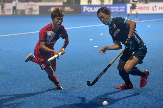 Hwang Tae-il, left, and Japan's Kawabe Kosei fight for the ball during a men's field hockey match between Japan and Korea at the Asian Championship Trophy tournament in Dhaka, Bangladesh on Wednesday. Korea are tied for second after holding Japan to a 3-3 draw. After two more preliminary matches, the top four teams will advance to the semifinals. [AFP/YONHAP]