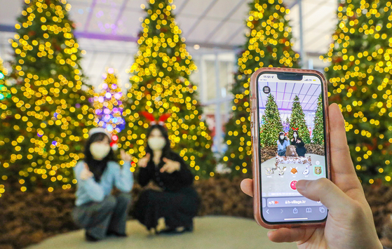 Models pose at an augmented-reality photo zone set up inside the "H Village" space on the seventh floor of Hyundai Department Store's Mok-dong branch in western Seoul on Sunday. The "H Village," zone inspired by Christmas, has about 50 Christmas trees and holiday-themed decorations. [HYUNDAI DEPARTMENT STORE]