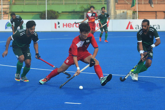 Lee Hye-seung, center, guides the ball past Pakistan's Afraz, left, and Ali Shan during the men's field hockey match between Pakistan and Korea at the Asian Championship Trophy tournament in Dhaka, Bangladesh, on Saturday. Korea held Pakistan to a draw and will advance to the semifinals as runner-up in the standings with one win and three draws, one win behind leader India. [AFP/YONHAP]