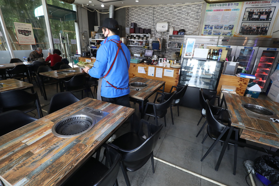 A restaurant owner works by herself at aunch time in Daegu on Sunday, a day after a stricter social distancing scheme went into effect. [YONHAP]