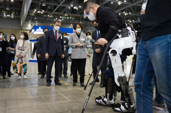 Lim Hye-sook, minister of science and ICT, watches a man who has been paralyzed for 26 years stand upright and walk with the help of robotic limbs that were presented at the 2021 Korea Science & Technology Fair held at Kintex in Goyang, Gyeonggi, on Wednesday. [MINISTRY OF SCIENCE AND ICT]