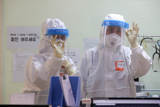 Medical staff in Level D protective suits give the O.K. hand sign in a negative pressure room in Hyemin Hospital, a Covid-19-dedicated hospital in Gwangjin District, eastern Seoul, on Tuesday. [WOO SANG-JO]